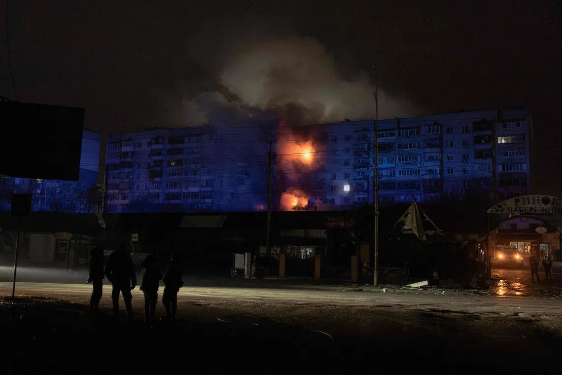 People look at a residential building on fire following a Russian drone attack on the city of Vyshhorod, in the Kyiv region early on Nov 30, 2025.