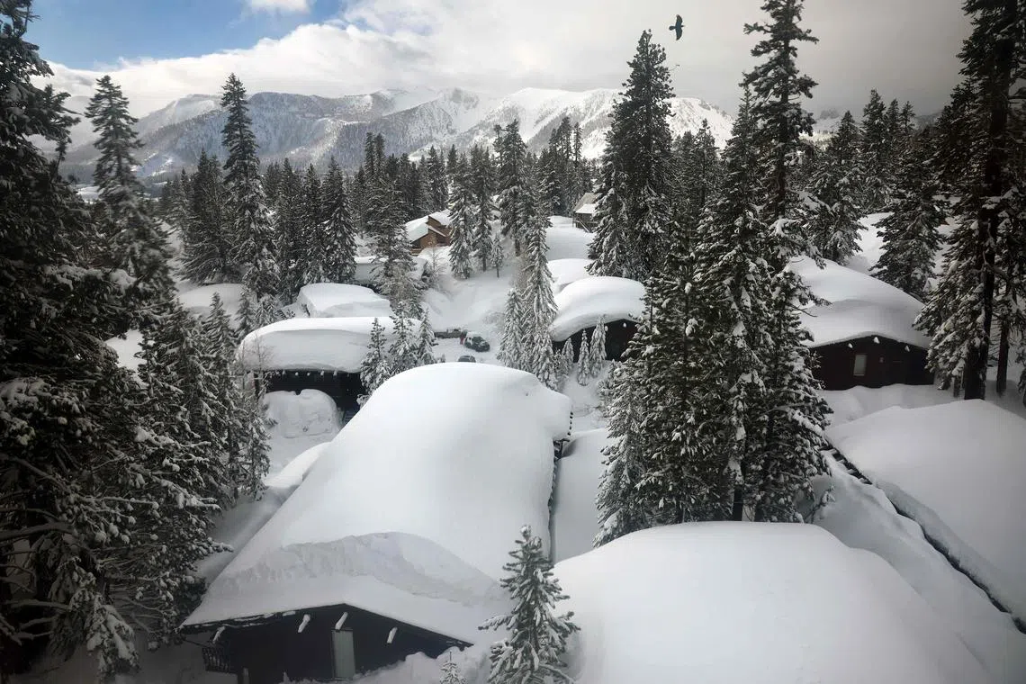 Rooftops of homes in the Sierra Nevada mountains are covered in snow, in the wake of an atmospheric river event, on March 12, 2023, in Mammoth Lakes, California. 