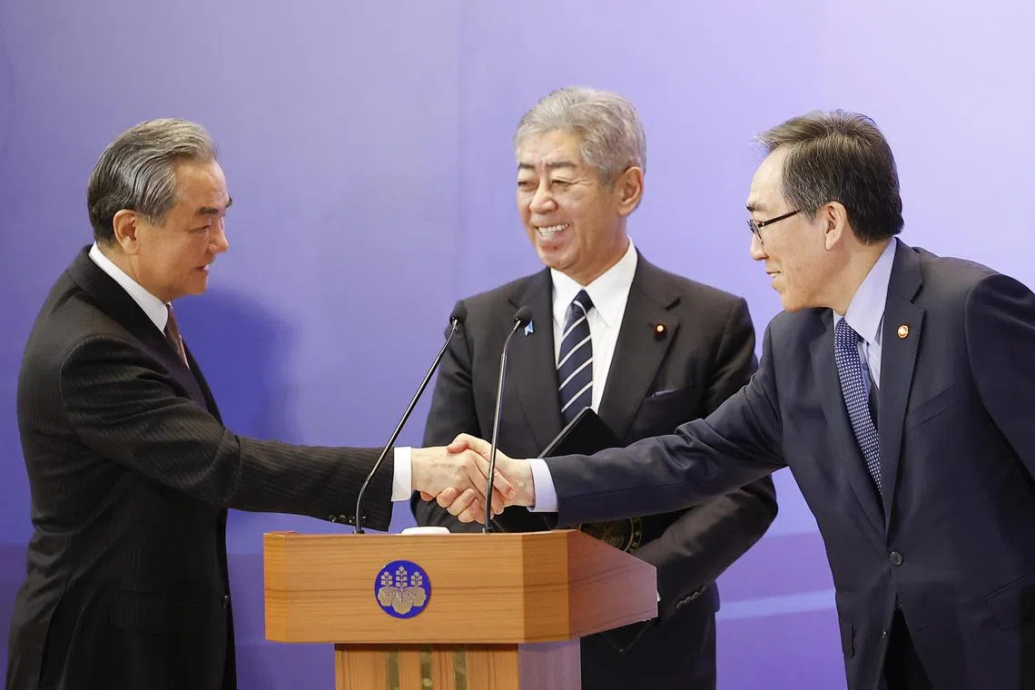 Chinese Foreign Minister Wang Yi (L) and South Korean Foreign Minister Cho Tae-yul (R) shake hands as Japanese Foreign Minister Takeshi Iwaya (C) smiles after a joint press conference at the 11th Japan-China-South Korea trilateral foreign ministers' meeting in Tokyo on March 22, 2025.