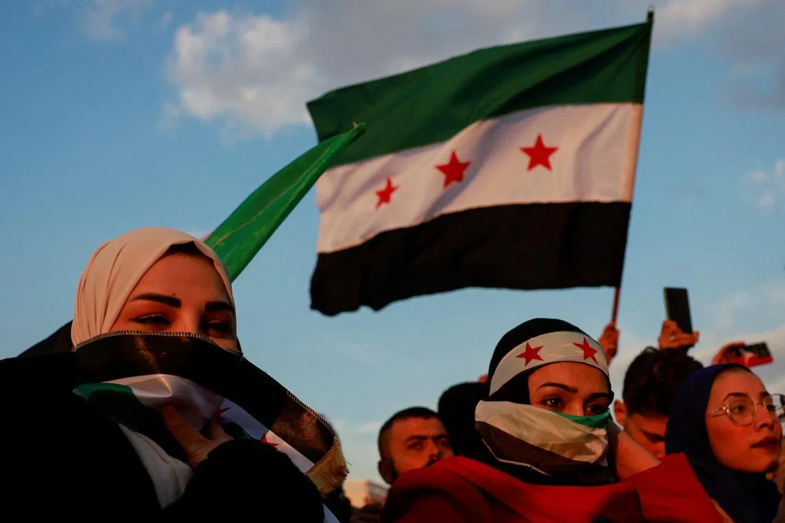 FILE PHOTO: A person waves a flag adopted by the new Syrian rulers, as people gather during a celebration called by Hayat Tahrir al-Sham (HTS) near the Umayyad Mosque, after the ousting of Syria's Bashar al-Assad, in Damascus, Syria, December 20, 2024. REUTERS/Ammar Awad/File Photo