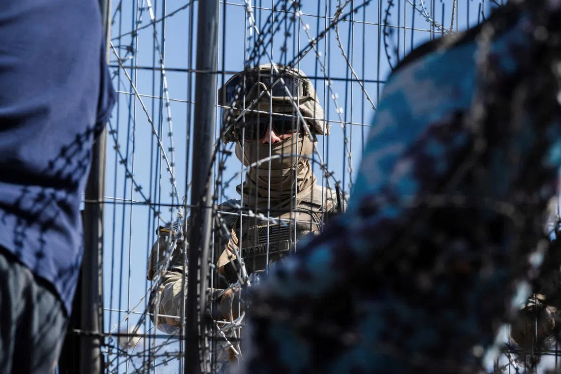 FILE PHOTO: A Texas law enforcement officer stands guard at the border as migrants cross from Mexico into El Paso, Texas, U.S., March 22, 2024.  REUTERS/Justin Hamel/File Photo