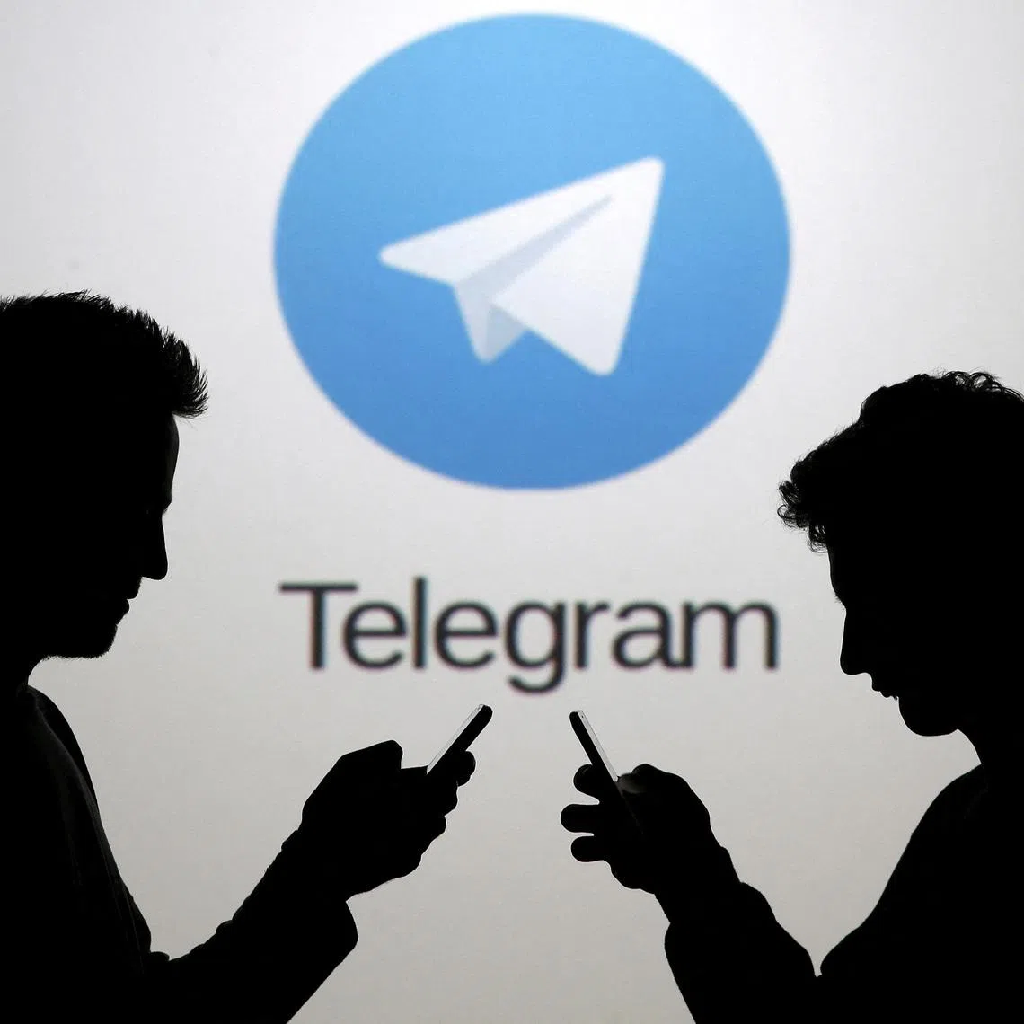 FILE PHOTO: Two men pose with smartphones in front of a screen showing the Telegram logo in this picture illustration taken in Zenica, Bosnia and Herzegovina November 18, 2015.  REUTERS/Dado Ruvic/File Photo