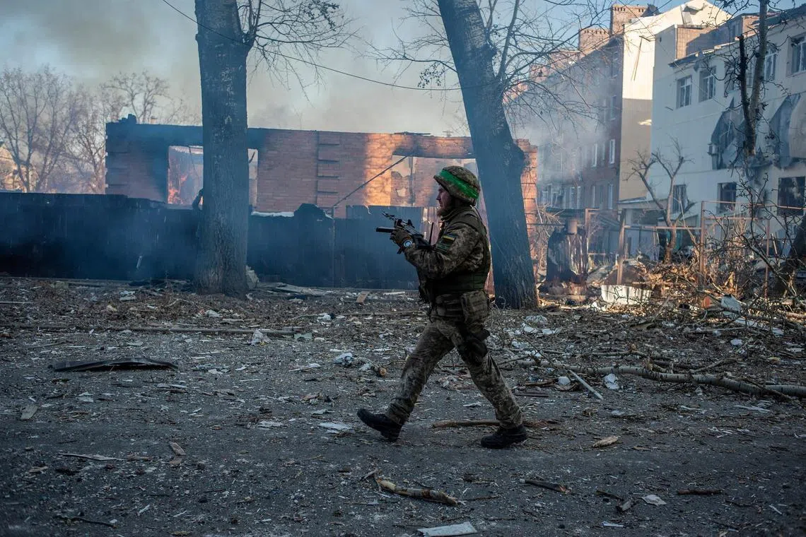 A Ukrainian serviceman walks next to a burning building in the front-line town of Bakhmut, in Ukraine's Donetsk region, on Feb 13, 2023.