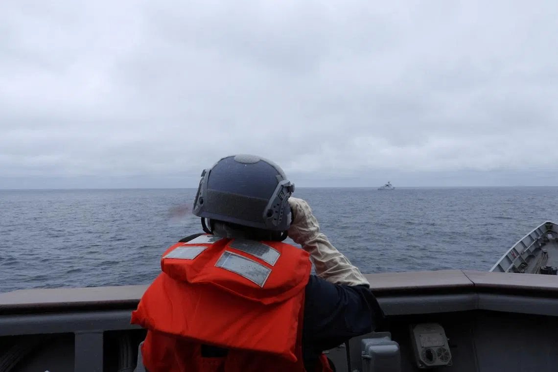 A Taiwanese sailor aboard a Taiwan Navy vessel looking towards a Chinese warship on waters off Taiwan's western coast on May 23.