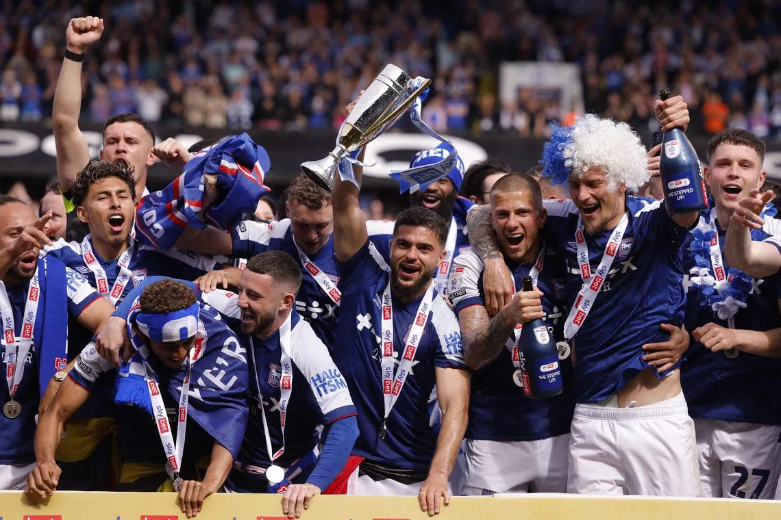 Ipswich players celebrate with a trophy and promotion to the Premier League after beating Huddersfield 2-0 at Portman Road on May 4, 2024.