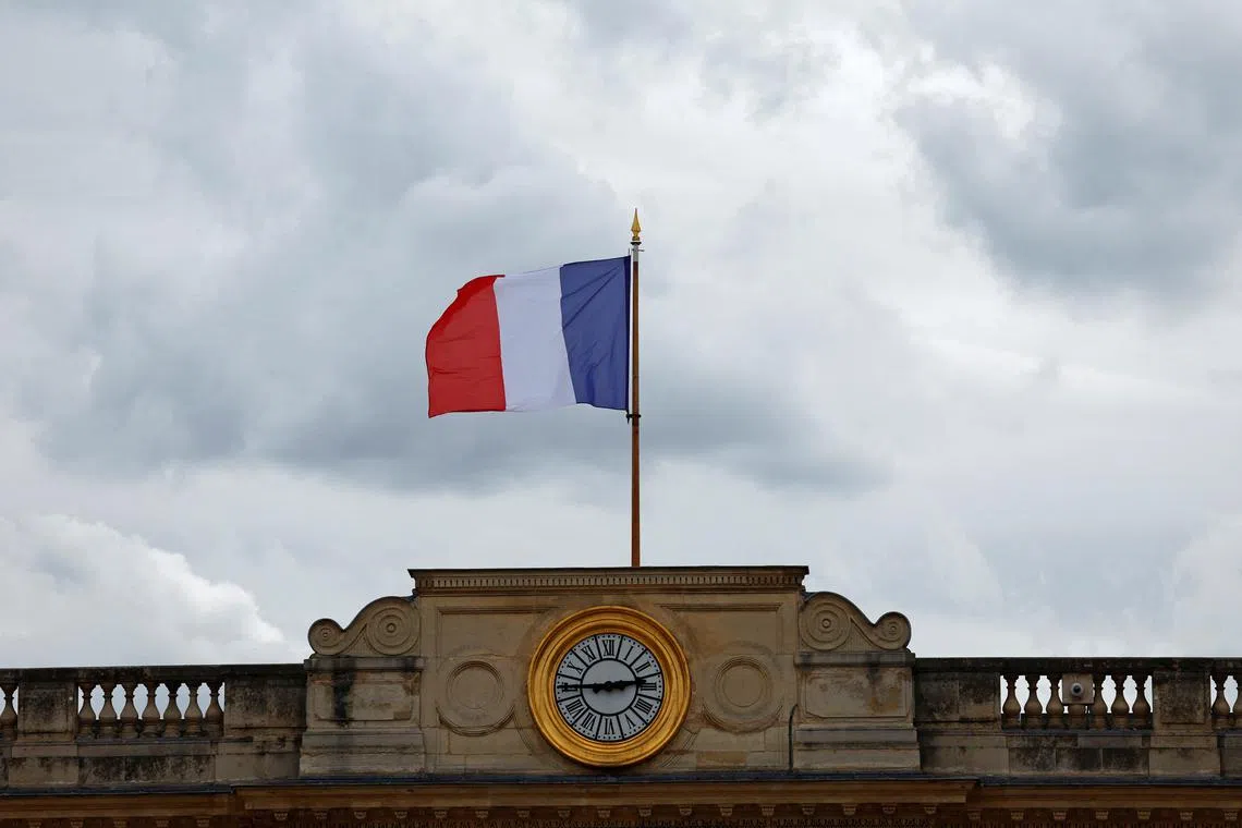 FILE PHOTO: A French flag flies above the National Assembly in Paris on day after the second round of the early French parliamentary elections, France, July 8, 2024. REUTERS/Gonzalo Fuentes/File Photo