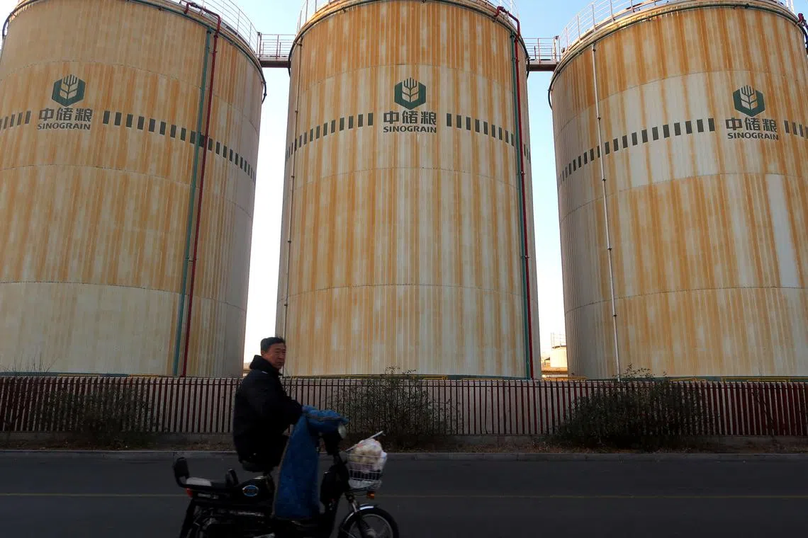 FILE PHOTO: A man cycles past storage facilities of China's state grain stockpiler Sinograin near Tianjin port, China December 12, 2019.  REUTERS/Yilei Sun/File Photo