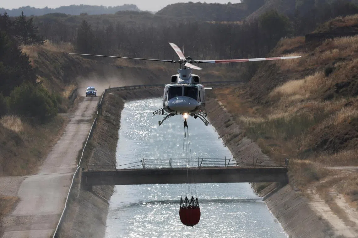 A firefighting helicopter loads water to battle wildfires affecting Zaragoza province, in Farasdues, Spain, on July 16.