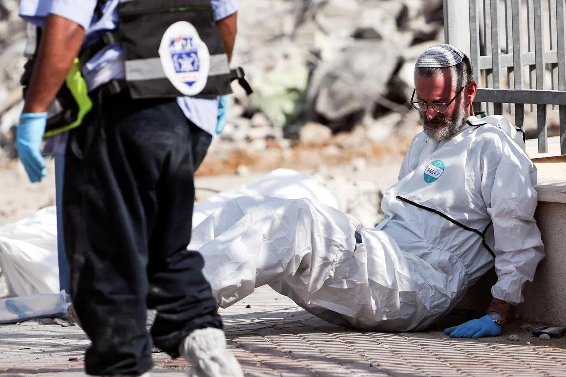 An Israeli rescue worker sits next to a dead body in Sderot, southern Israel.