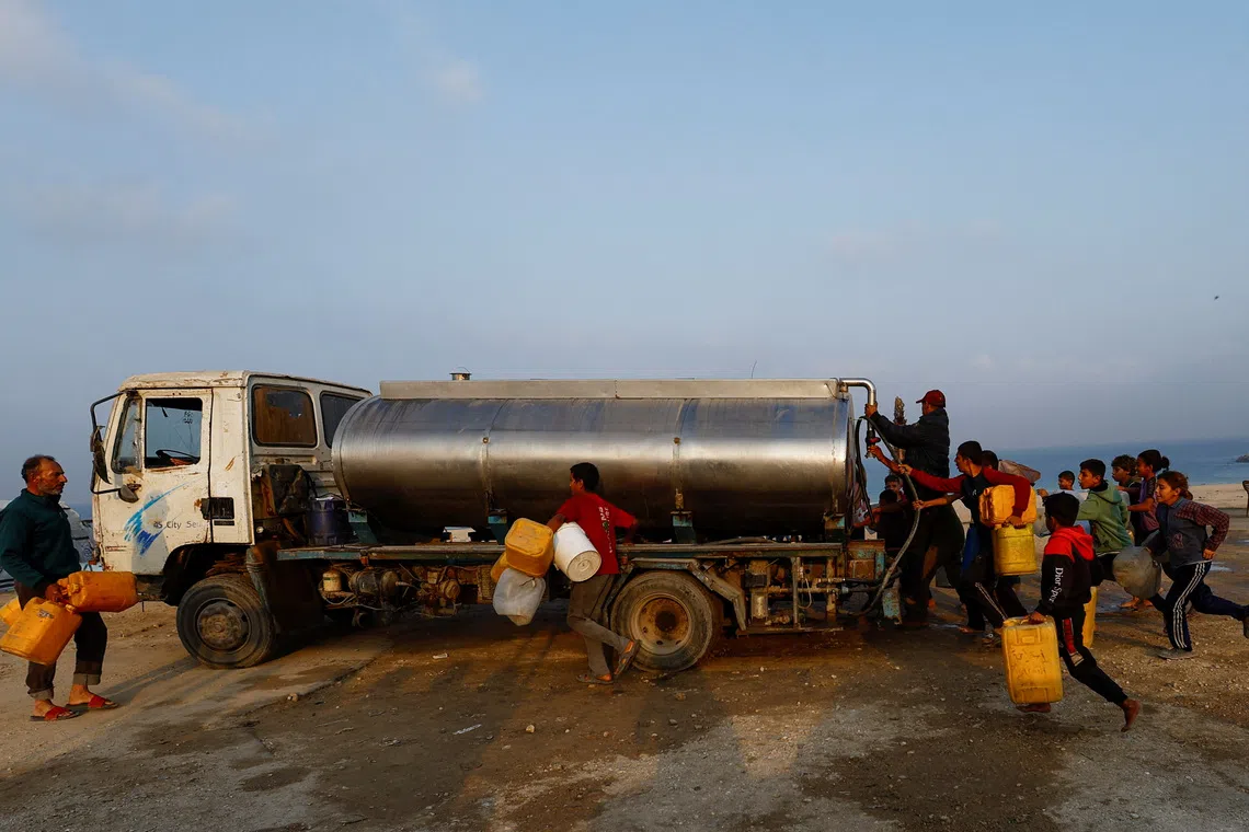 Displaced Palestinians run to fill containers with water amid a ceasefire between Israel and Hamas, in Gaza City, November 6, 2025. REUTERS/Mahmoud Issa
