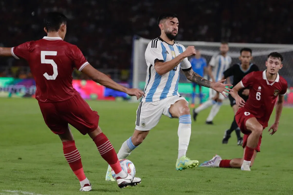 Leandro Paredes (centre) of Argentina vies for the ball against Rizky Ridho (left) of Indonesia.