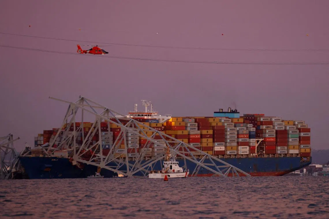 A U.S. Coast Guard search and rescue helicopter flies over the Dali cargo vessel, which crashed into the Francis Scott Key Bridge causing it to collapse in Baltimore, Maryland, U.S., March 26, 2024.  REUTERS/Julia Nikhinson