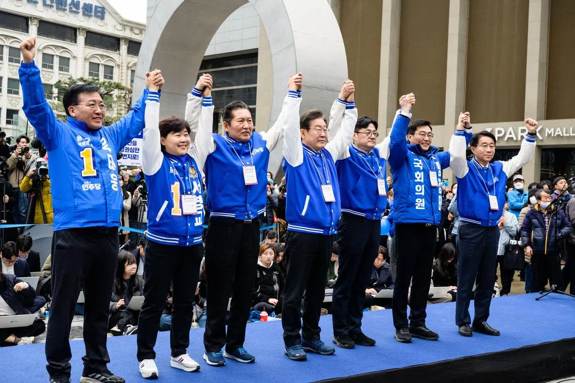 South Korea's main opposition Democratic Party of Korea leader Lee Jae-myung (C) and other party members join hands at a campaign event for the upcoming parliamentary elections.