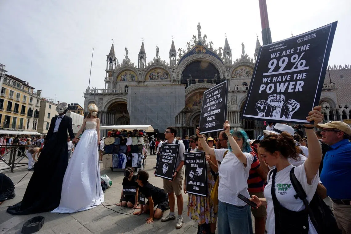 Activists from the 'Extinction Rebellion' group staging a protest against over-tourism and Amazon founder Jeff Bezos' wedding in Venice, at St Mark square in Venice on June 26, 2025. 
