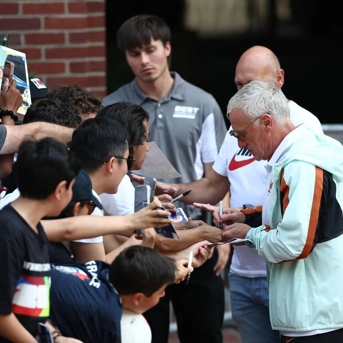 France’s head coach Didier Deschamps signing autographs as the team depart from their hotel to travel to Miami on July 16.