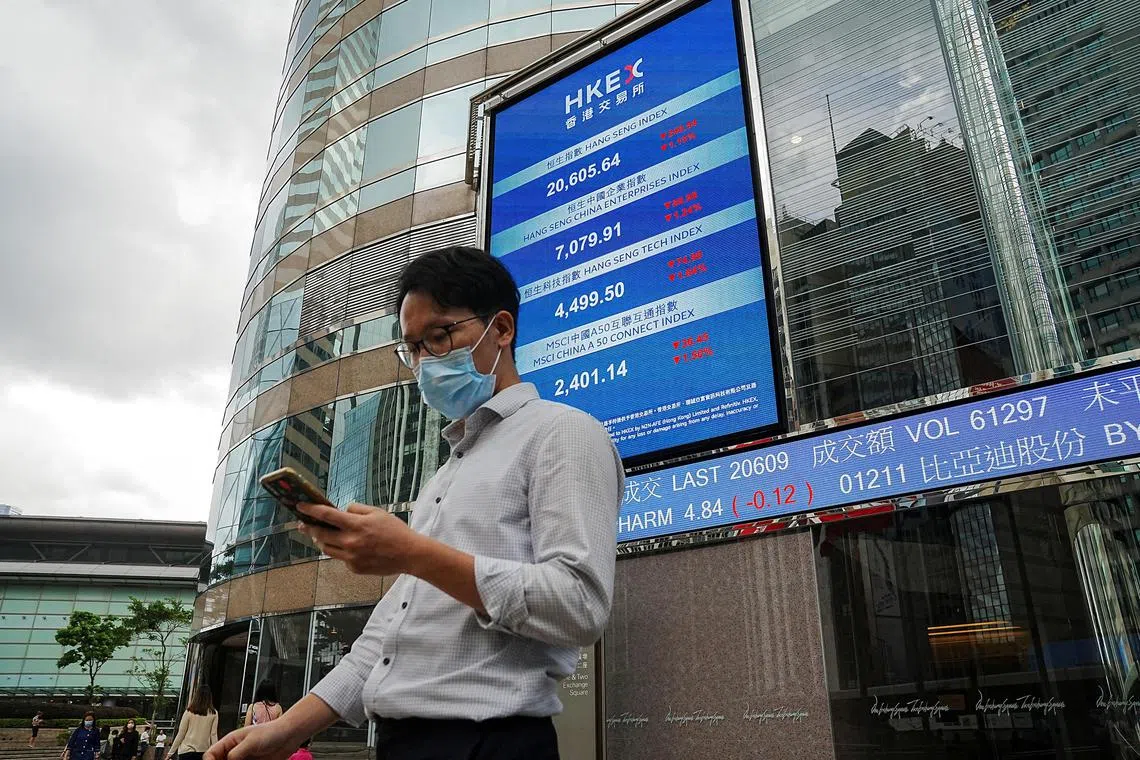 People walk past a screen displaying the Hang Seng stock index outside Hong Kong Exchanges, in Hong Kong, China, July 19, 2022. REUTERS/Lam Yik/File Photo