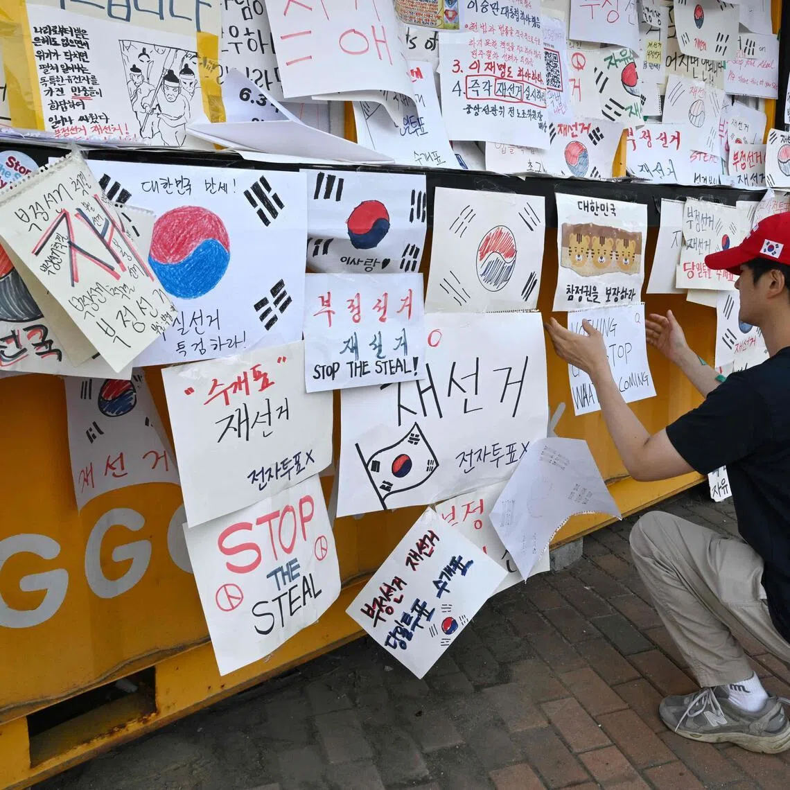 A South Korean protester attaches a message calling for a rerun of the local elections due to a shortage of ballot papers outside a vote-counting centre in Seoul on June 10, 2026.