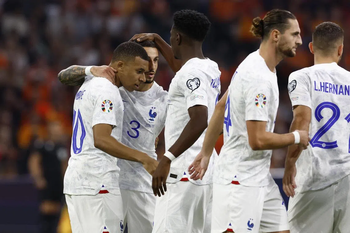 Kylian Mbappe celebrates scoring France's first goal with Jonathan Clauss and Aurelien Tchouameni.