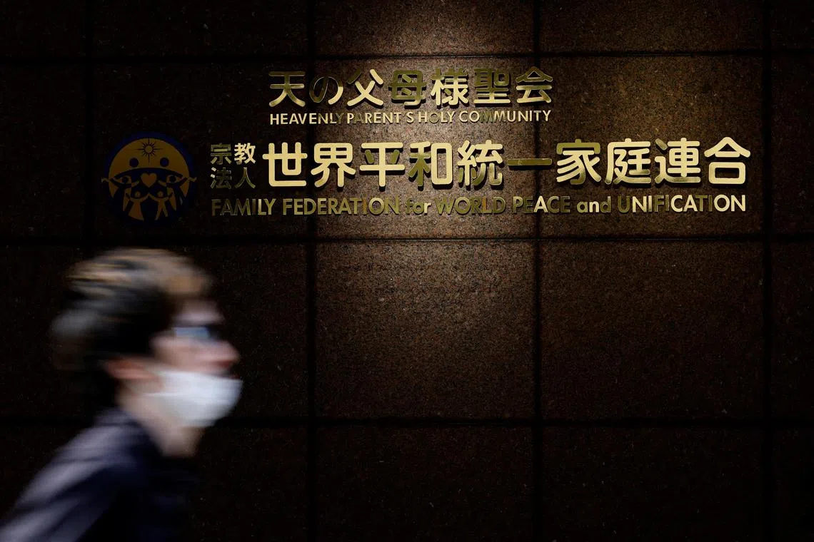 FILE PHOTO: A person walks past the sign of Family Federation for World Peace and Unification, more commonly known as the Unification Church, at its Tokyo headquarters in Tokyo, Japan August 29, 2022. REUTERS/Kim Kyung-Hoon/File Photo