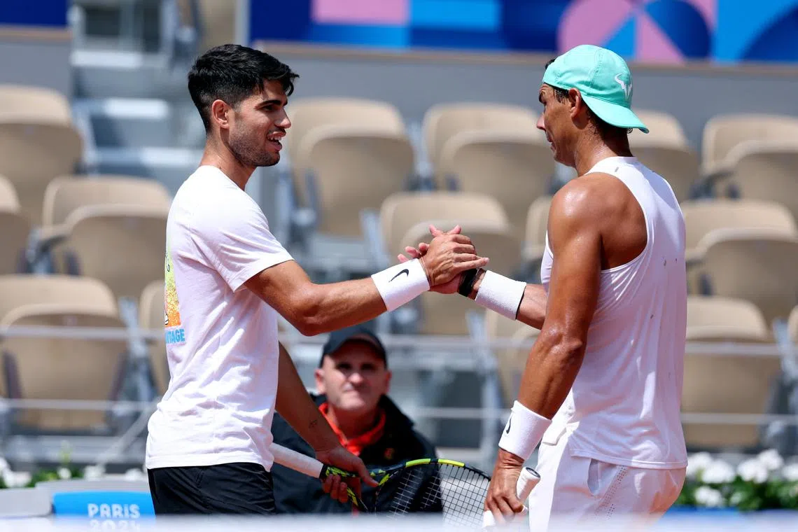 Paris 2024 Olympics - Tennis Training - Roland Garros Stadium, Paris, France - July 24, 2024. Carlos Alcaraz of Spain shakes hands with Rafael Nadal of Spain during training. REUTERS/Claudia Greco