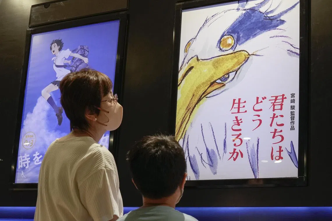 epa10747256 Visitors look at a poster (R) of Japanese anime Studio Ghibli's Hayao Miyazaki's first film in a decade displayed at a movie theater in Tokyo, Japan, 15 July 2023. The Miyazaki's final film titled 'Kimitachi wa do ikiruka?' was released on 14 July 2023 without special information in advance.  EPA-EFE/KIMIMASA MAYAMA
