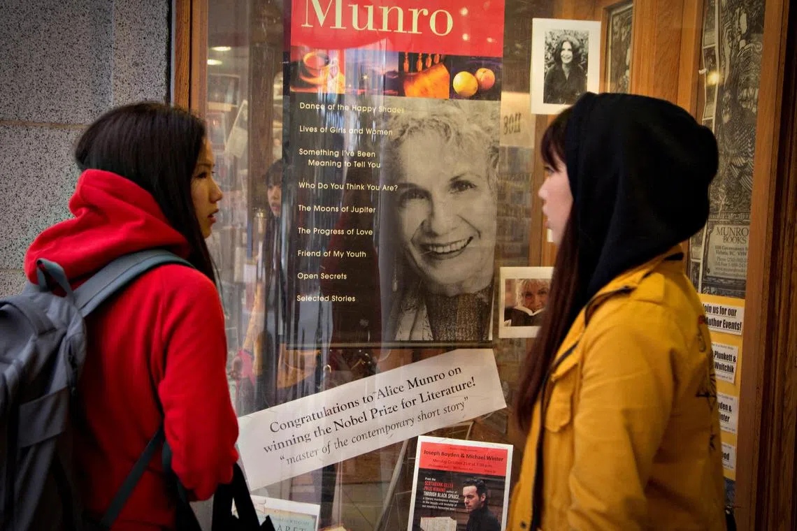 Customers look at a window display congratulating Canadian author Alice Munro at bookstore Munro's Books after she won the Nobel Prize for Literature in Victoria, British Columbia, on Oct 10, 2013. 