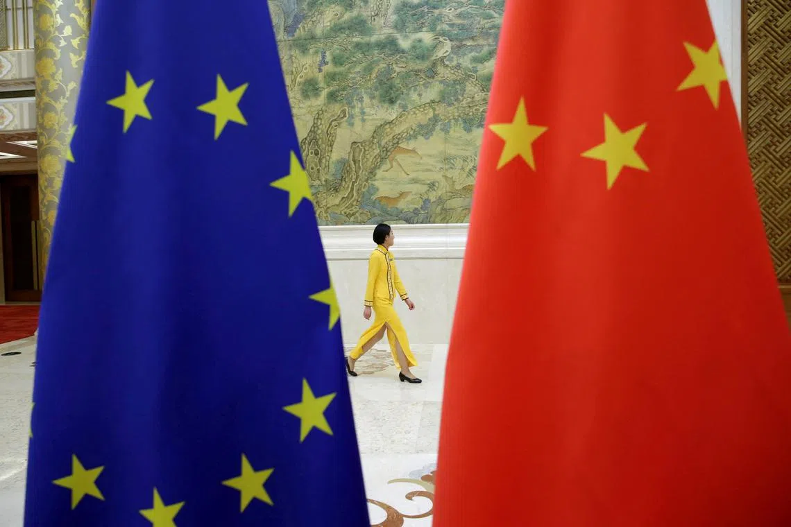 FILE PHOTO: An attendant walks past EU and China flags ahead of the EU-China High-level Economic Dialogue at Diaoyutai State Guesthouse in Beijing, China June 25, 2018. REUTERS/Jason Lee/File Photo