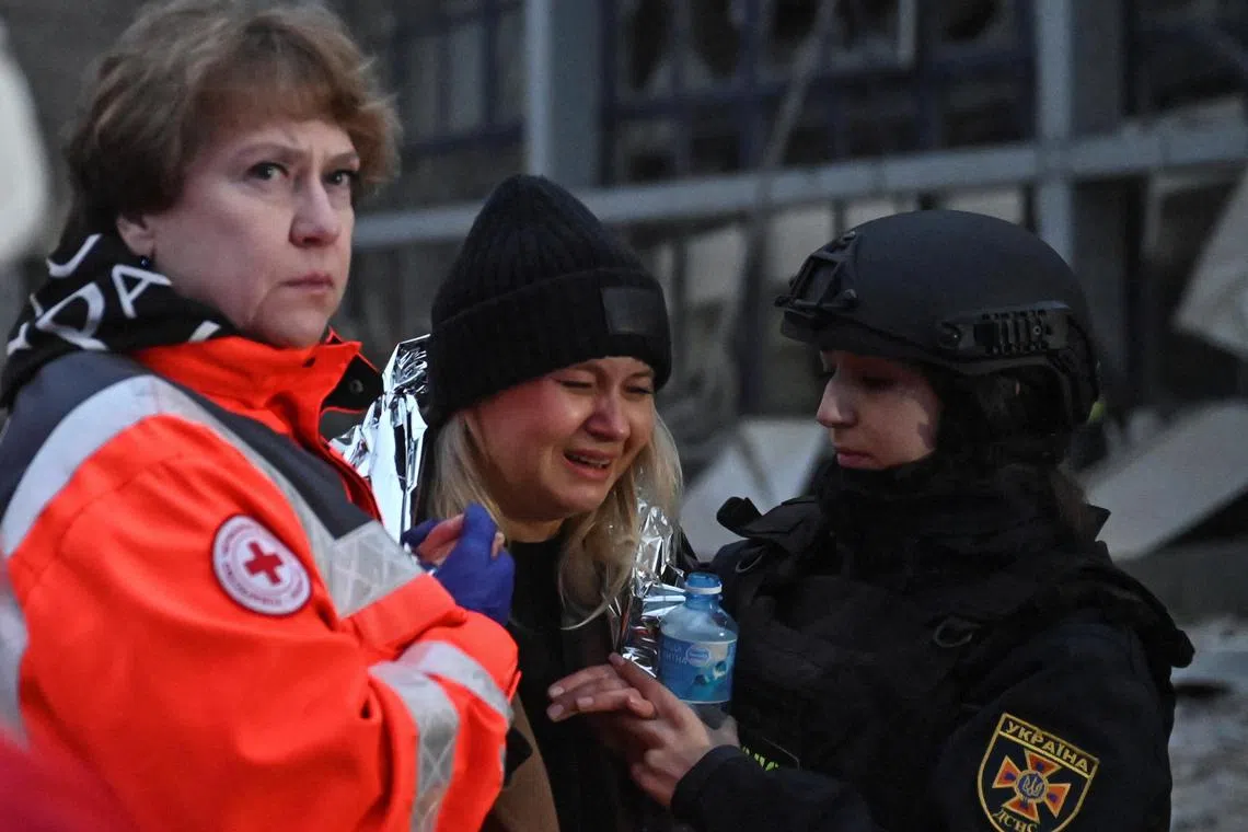 A paramedic and a rescuer helping a woman at the site of a Russian missile strike in the Ukrainian city of Zaporizhzhia, on Dec 10.