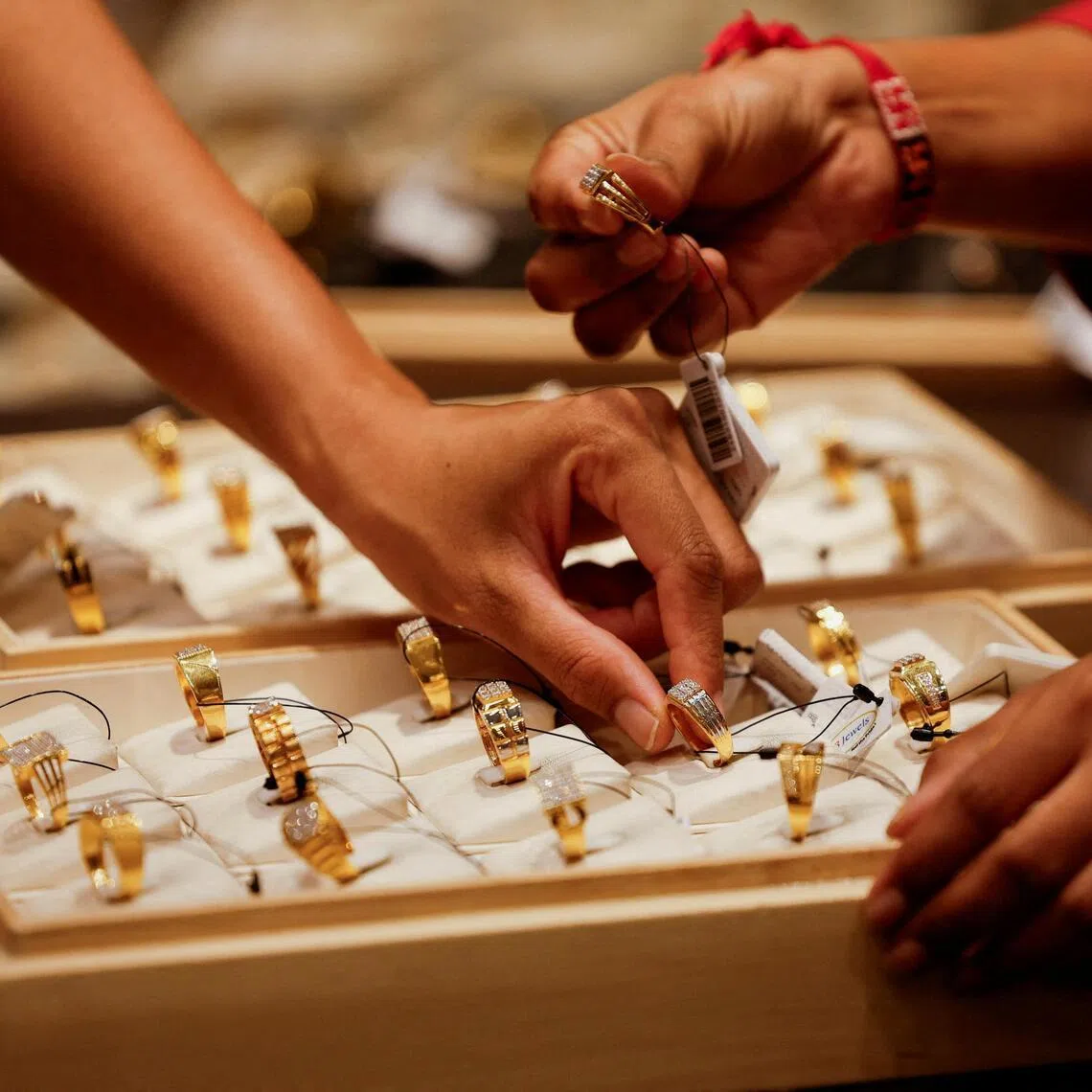 FILE PHOTO: A salesperson shows a gold ring to customers at a jewellery showroom in Ahmedabad, India, October 8, 2025. REUTERS/Amit Dave/File Photo