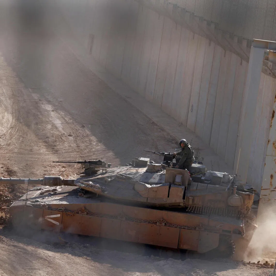 An Israeli military tank patrols close to a concrete wall along the border fence separating northern Israel from southern Lebanon.