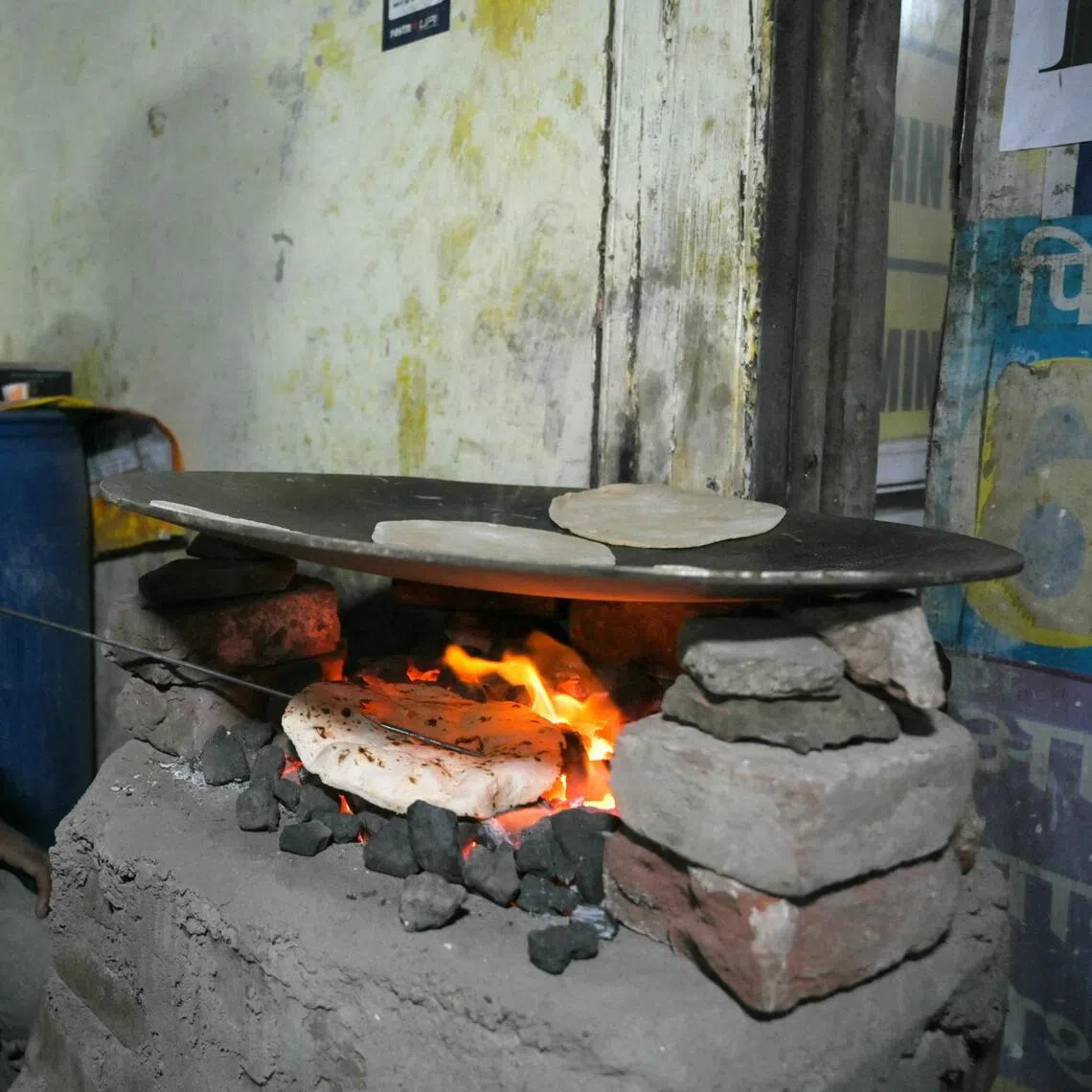 A man cooking bread on a coal-fired stove at a roadside eatery in Ahmedabad amid ongoing oil and gas import disruptions caused by the Middle East war, on March 25, 2026.