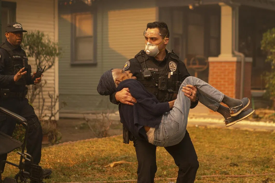 Laverna Sharpe, who is 101, is carried from her home by Pasadena Police officer Christian Banuelos during the Eaton Fire in Los Angeles county on Jan 8, 2025. 