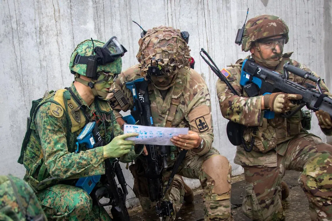 A soldier from the Singapore Army (left) working with his counterparts from the US Army during urban operations at Safti City for Exercise Tiger Balm.
