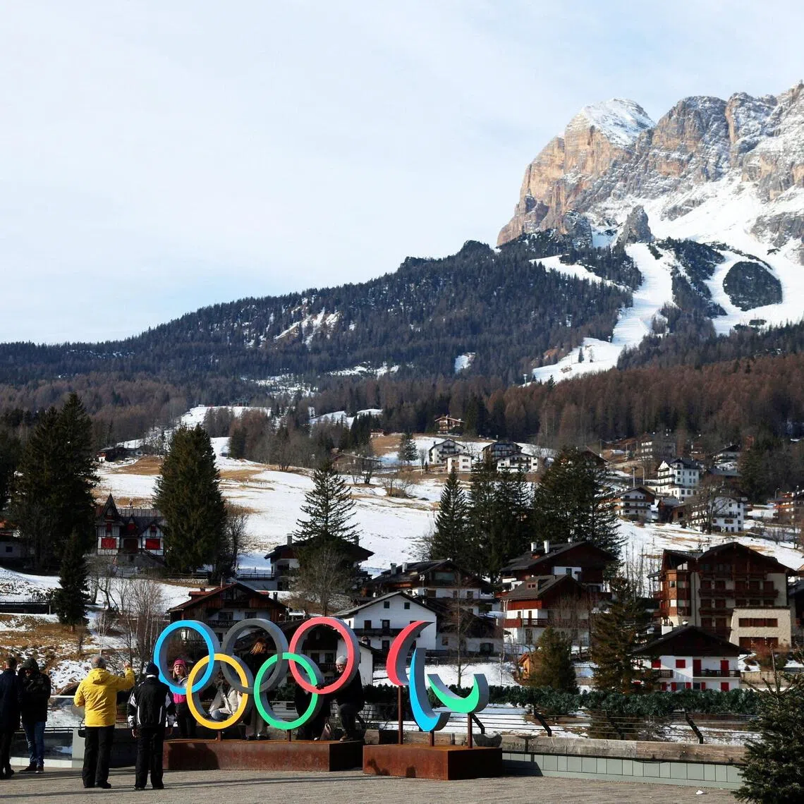 People posing for a picture in front of the Olympic rings and Olympia delle Tofane track, which will host the women alpine skiing competition at the Milano Cortina Winter Olympic Games.