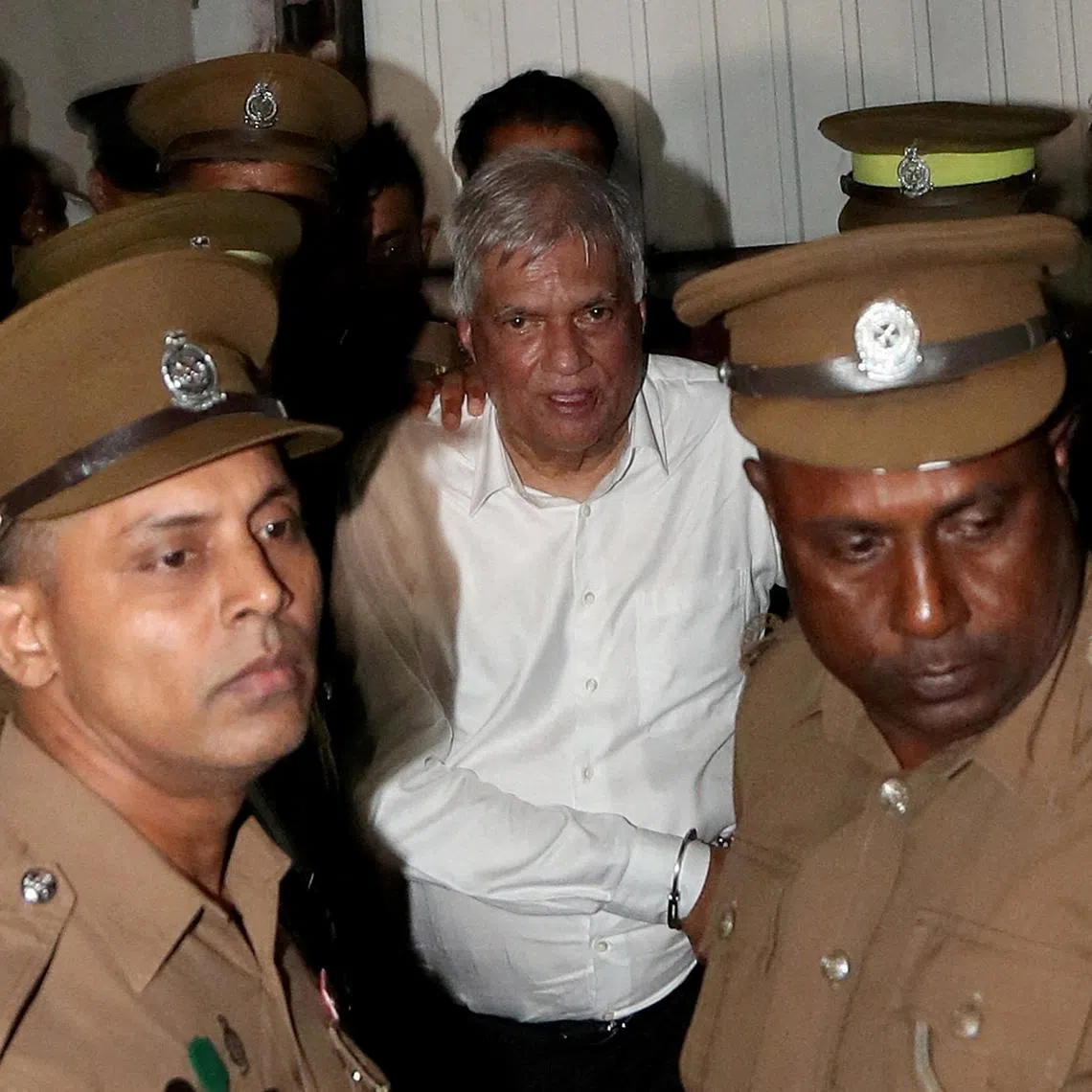 FILE PHOTO: Sri Lanka's former President Ranil Wickremesinghe is escorted by prison and police officials as he leaves the Magistrate’s Court in Colombo, Sri Lanka, August 22, 2025. REUTERS/Lahiru Harshana/File Photo