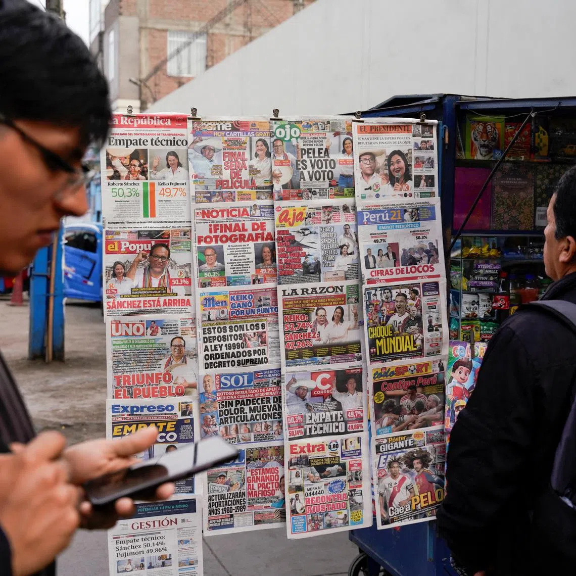 A man looks at a newspaper stand with headlines showing early results of a runoff between conservative presidential candidate Keiko Fujimori and left-wing candidate Roberto Sanchez, as Fujimori kept a slight lead over Sanchez, with over 90% of the votes counted, according to an official tally, in Lima, Peru, June 8, 2026. REUTERS/Leslie Moreno
