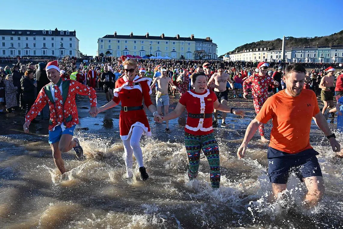 Participants take part in a Boxing Day Sea Dip off the coast at llandudno, north Wales on December 26, 2024. The Lions Club of Llandudno's Boxing Day Sea Dip is the final event in the clubs year of fund raising. Prizes are awarded for best fancy dress. (Photo by Paul ELLIS / AFP)