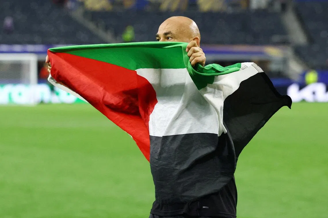 Egypt coach Hossam Hassan celebrates with a Palestine flag after Egypt eliminated Australia in the last 32 in Dallas on July 3.