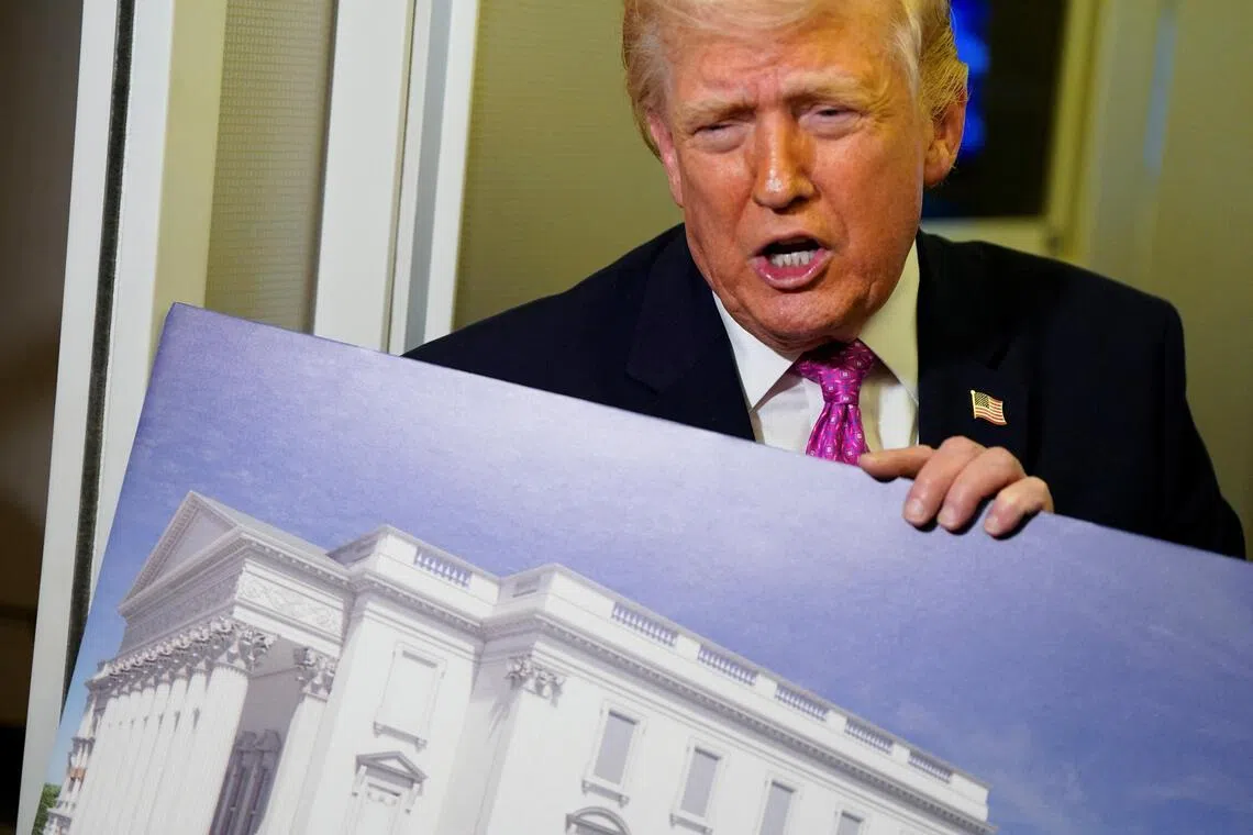 US President Donald Trump talking to members of the media on March 29, aboard Air Force One, while holding up renderings of the planned White House ballroom.