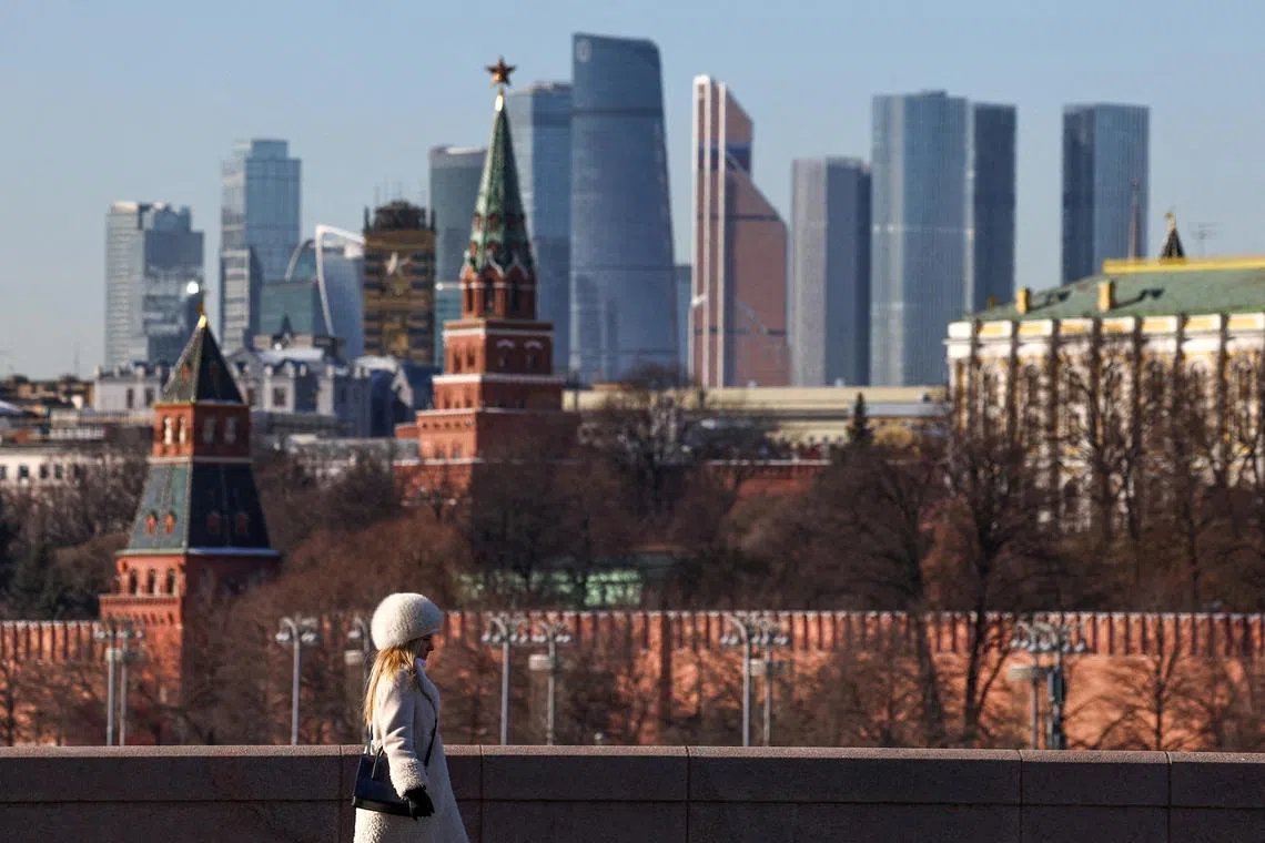FILE PHOTO: A woman walks along a bridge, with the Moscow City business centre and the Kremlin wall seen in the background, on a sunny day in Moscow, Russia, February 24, 2025. REUTERS/Evgenia Novozhenina//File Photo