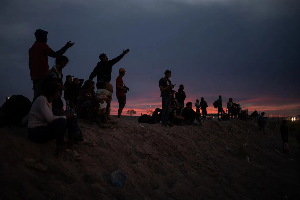 Migrants from South and Central America point towards the United States as they stand atop the bank of the Rio Grade river while searching for an entry point into El Paso, Texas, U.S., from Ciudad Juarez, Mexico, April 24, 2024. REUTERS/Adrees Latif/File Photo