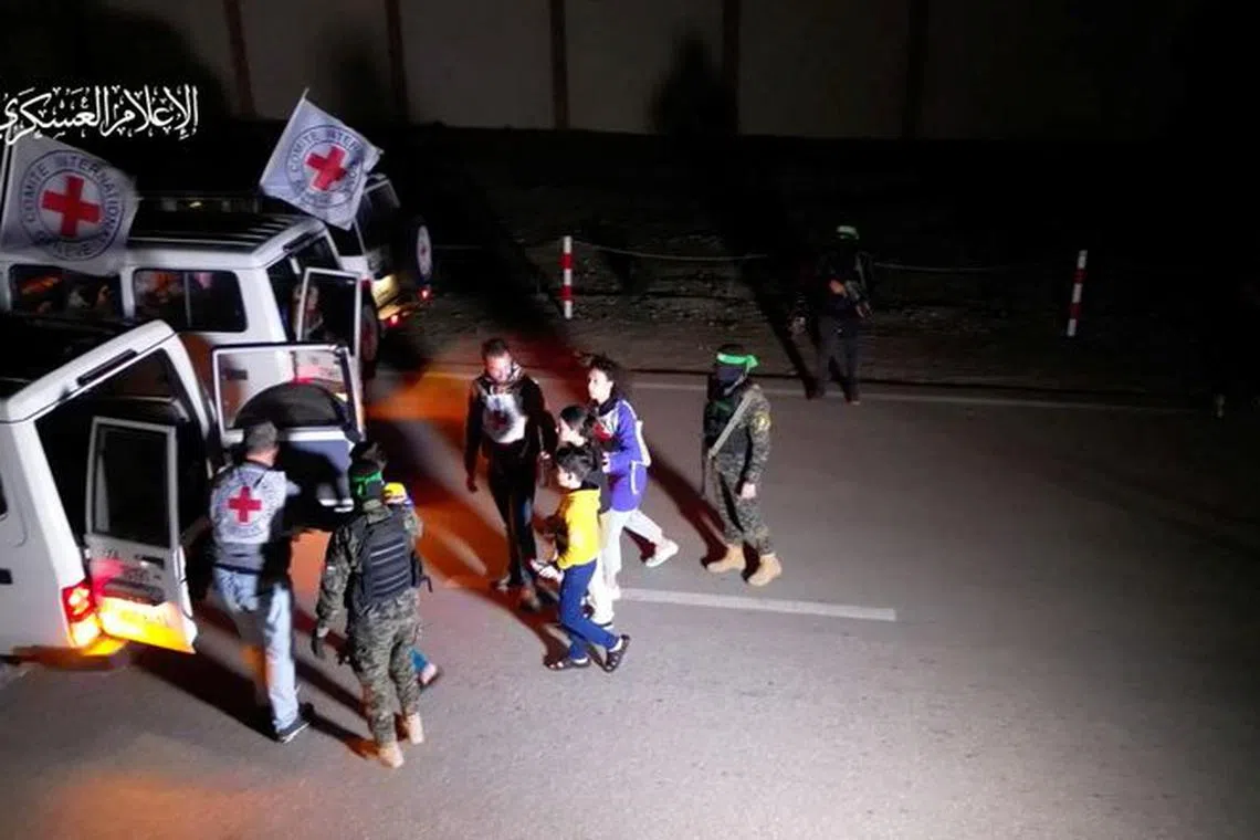FILE PHOTO: Hostages who were abducted by Hamas gunmen during the October 7 attack on Israel, are handed over by Hamas militants to members of the International Committee of the Red Cross, as part of a hostages-prisoners swap deal between Hamas and Israel amid a temporary truce, in an unknown location in the Gaza Strip, in this screengrab taken from video released November 27, 2023. Hamas Military Wing/Handout via REUTERS/File photo