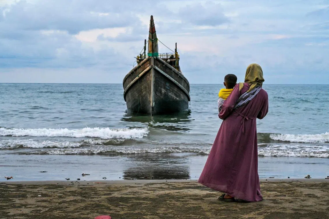A woman with her child looks at a boat which carried Rohingya refugees to the Laweueng beach in Pidie district of Aceh province, on Dec 10. More than 300 Rohingya refugees, mostly women and children, were stranded on the coast of western Indonesia after being adrift at sea for weeks, the latest in the biggest wave of arrivals since 2015. 