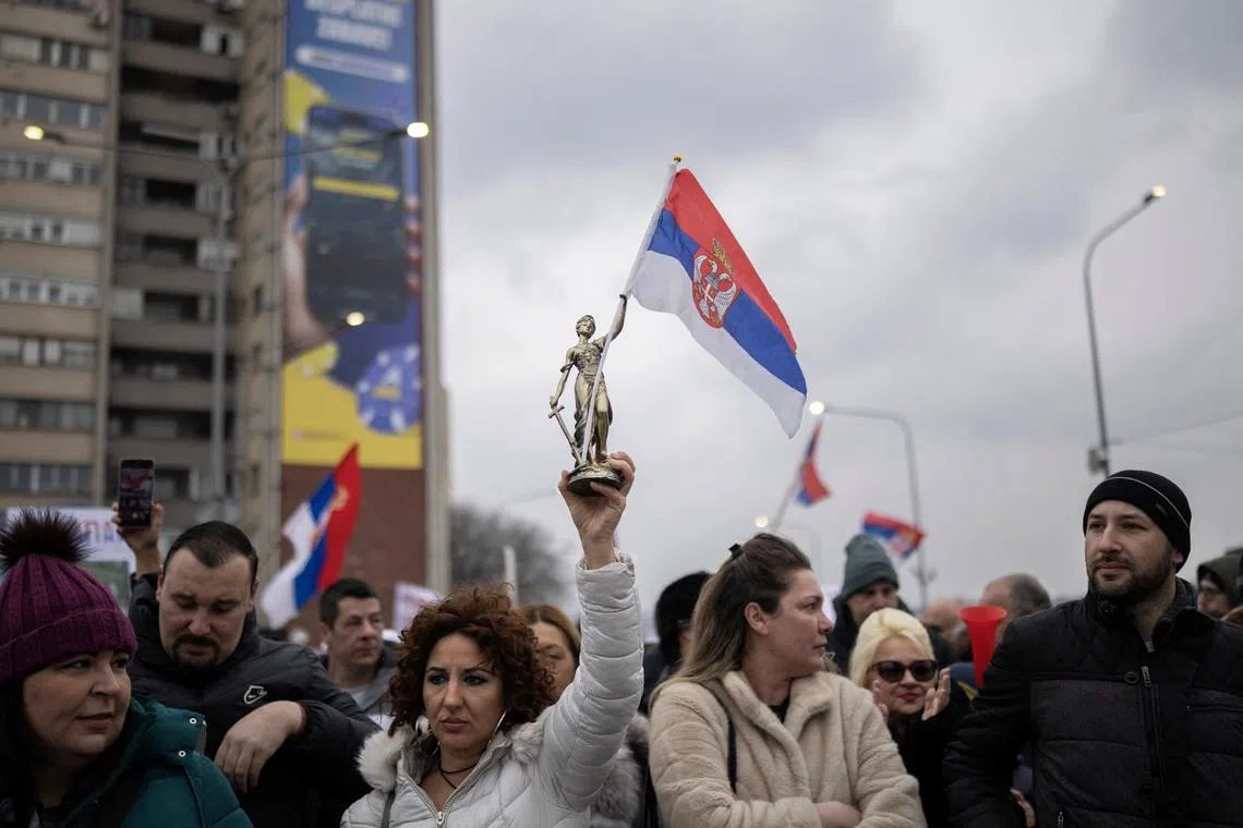 A woman holds a statuette of Lady Justice holding a Serbian national flag, during a protest over the fatal November 2024 Novi Sad railway station roof collapse, in Kragujevac, Serbia February 15, 2025. REUTERS/Alkis Konstantinidis