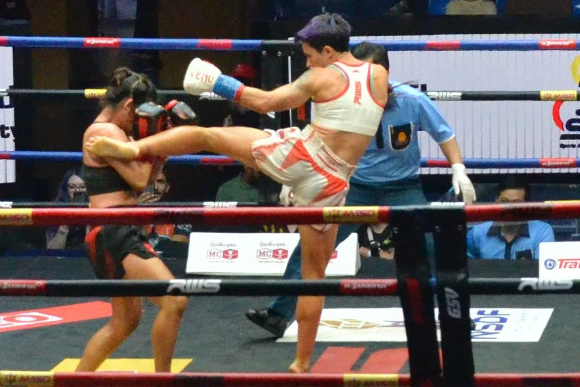 A Spanish muay thai fighter executes a roundhouse kick on her Thai opponent during a match at Rajadamnern Stadium on Oct 21.