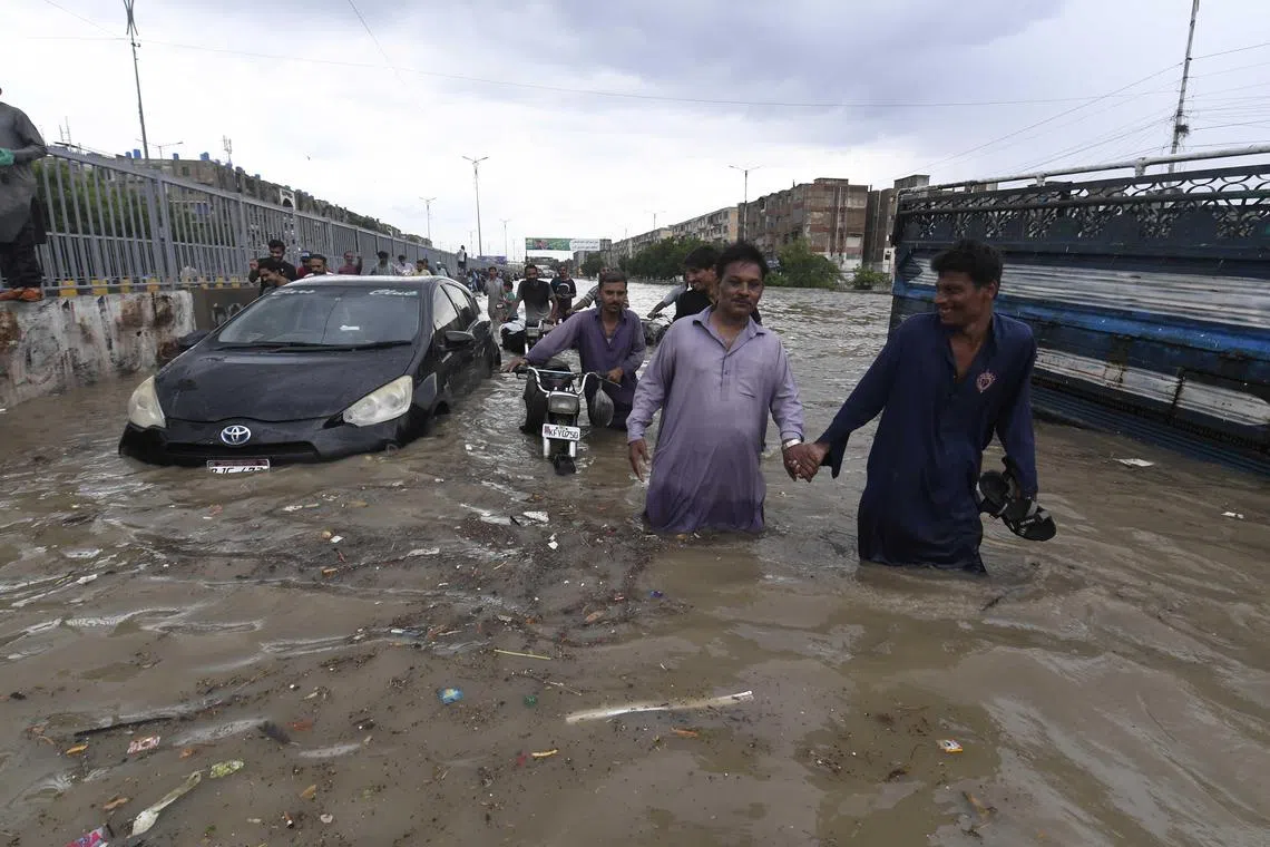 People wading through heavy monsoon rains in Karachi on Aug 19.  
