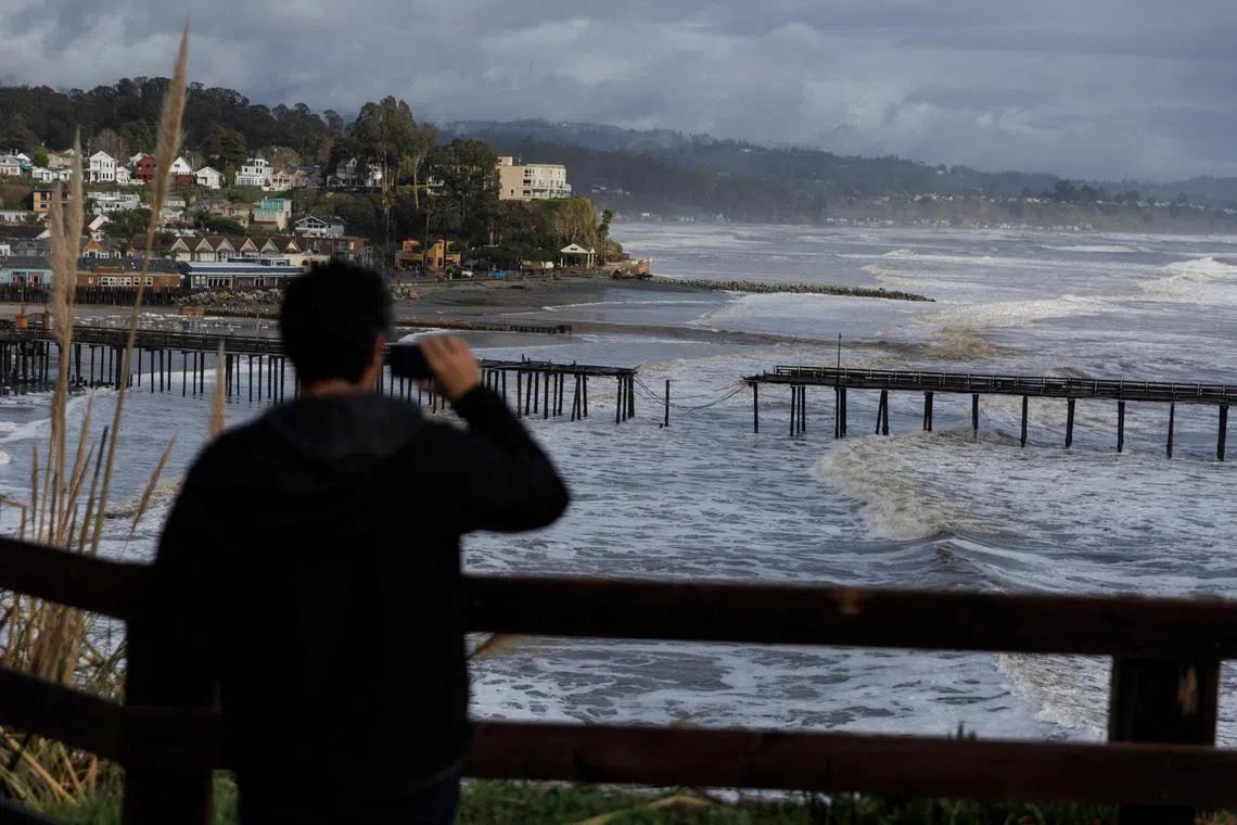 A local resident takes picture of a damaged pier after rainstorms known as "atmospheric river" slammed northern California.
