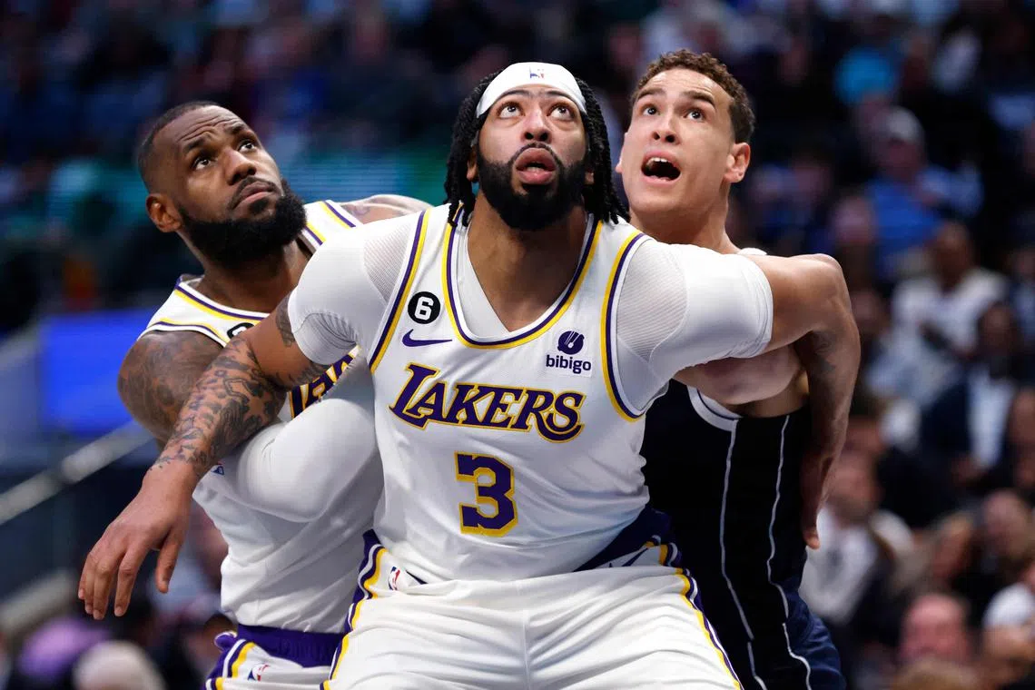 Anthony Davis (No. 3) and teammate LeBron James of the Los Angeles Lakers boxing out Mavericks' Dwight Powell en route to a 111-108 win on Sunday.