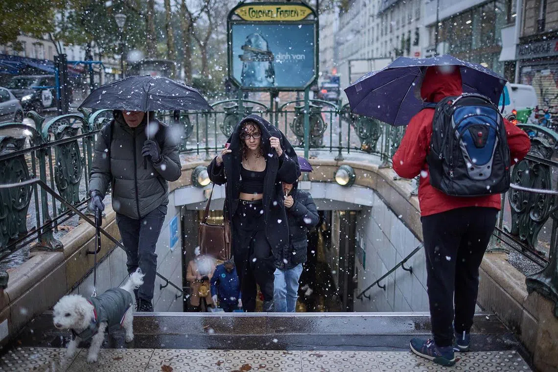 TOPSHOT - A commuter exits Colonel Fabien Metro station in heavy snowfall as Paris is placed under the second highest weather warning by the French national weather service for snow, in central Paris on November 21, 2024. Snow all the way to the plains, temperatures worthy of January: the first flakes of storm Caetano fell in France on November 21, where 54 departments are on 'orange alert' for snow, ice and wind. (Photo by Kiran RIDLEY / AFP)