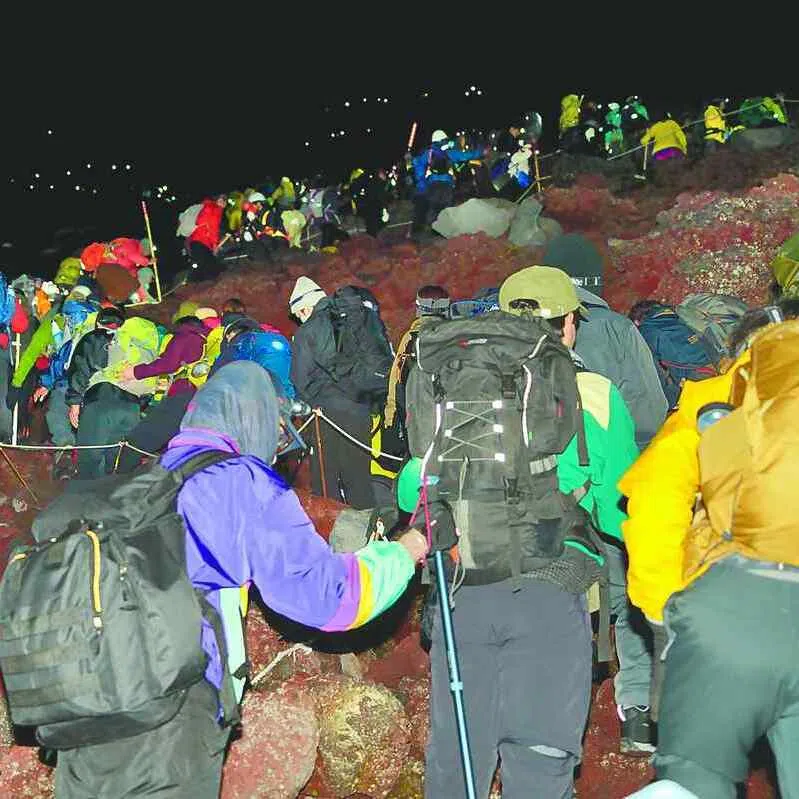 A long line of climbers on Mount Fuji make their way toward the summit at night on Aug 16.